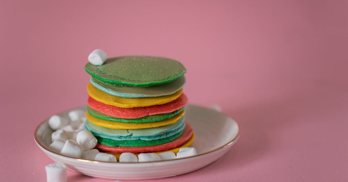 Stacked Booster Candy Crush - High angle of stack of multicolored appetizing pancakes stacked on plate with soft white marshmallows against pink background