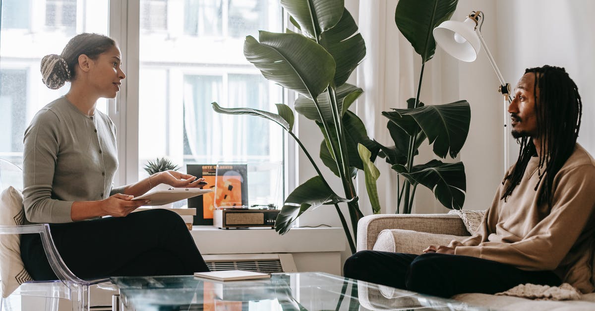 Stress recovery in town without abbey or tavern - Side view of professional female African American therapist sitting in front of black male patient during psychotherapy session in office