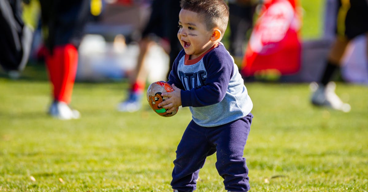 Succeed in baby rocking game in Tomodachi? - Boy in Purple Long Sleeves Shirt and Purple Pants Holding Brown Football