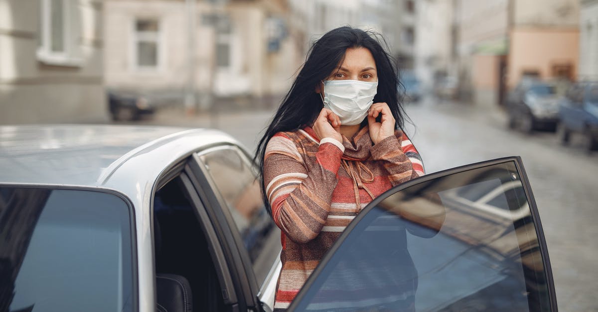 Summon out of the world - Young woman wearing medical mask standing near automobile on empty urban street