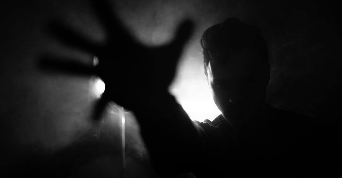 Super Secret Room with black poop and spikes - Black and white of anonymous male reaching out hand to camera while standing near wall with lamp in dark room