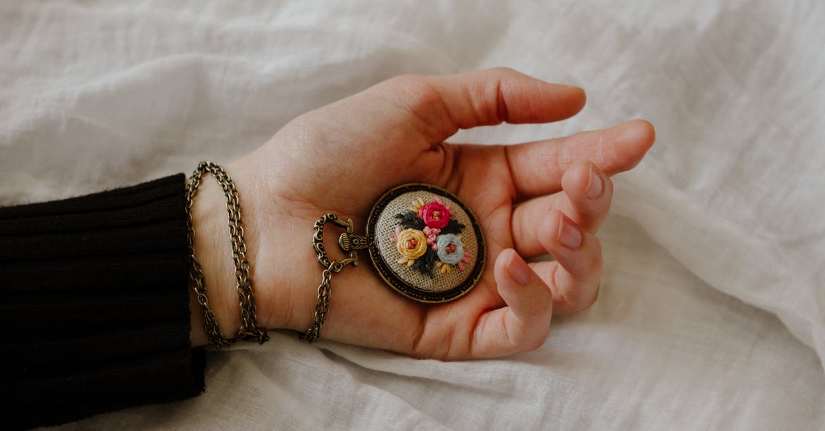 There’s only one hand on my Fez Clock - Top view of crop anonymous female with vintage chain watch on hand on white fabric