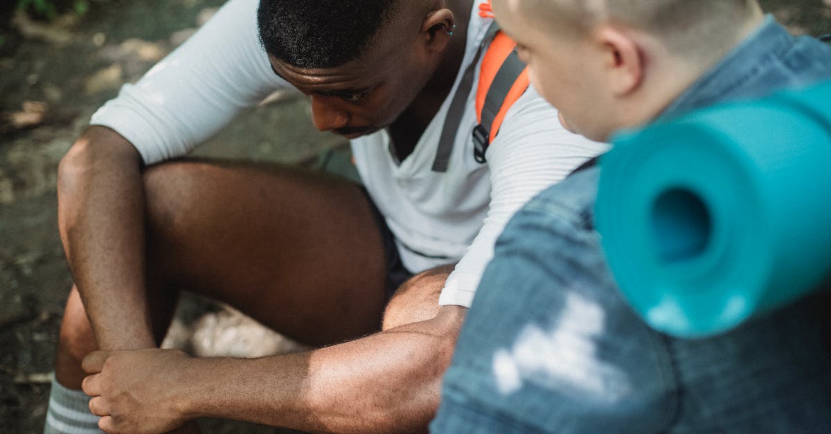 Trouble with Guard Break - From above of tired African American male hiker having break in trekking with friend in woods