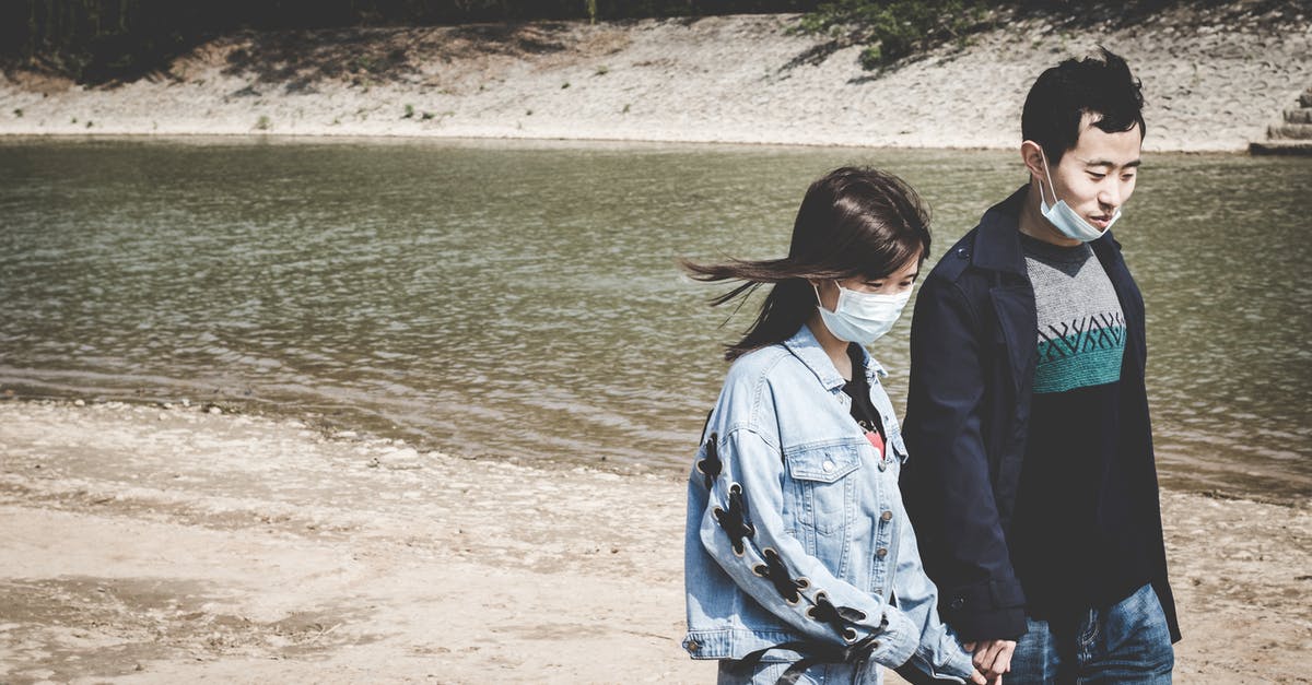 Unlock a redstone repeater after a period of time - Asian couple in masks holding hands while walking near river