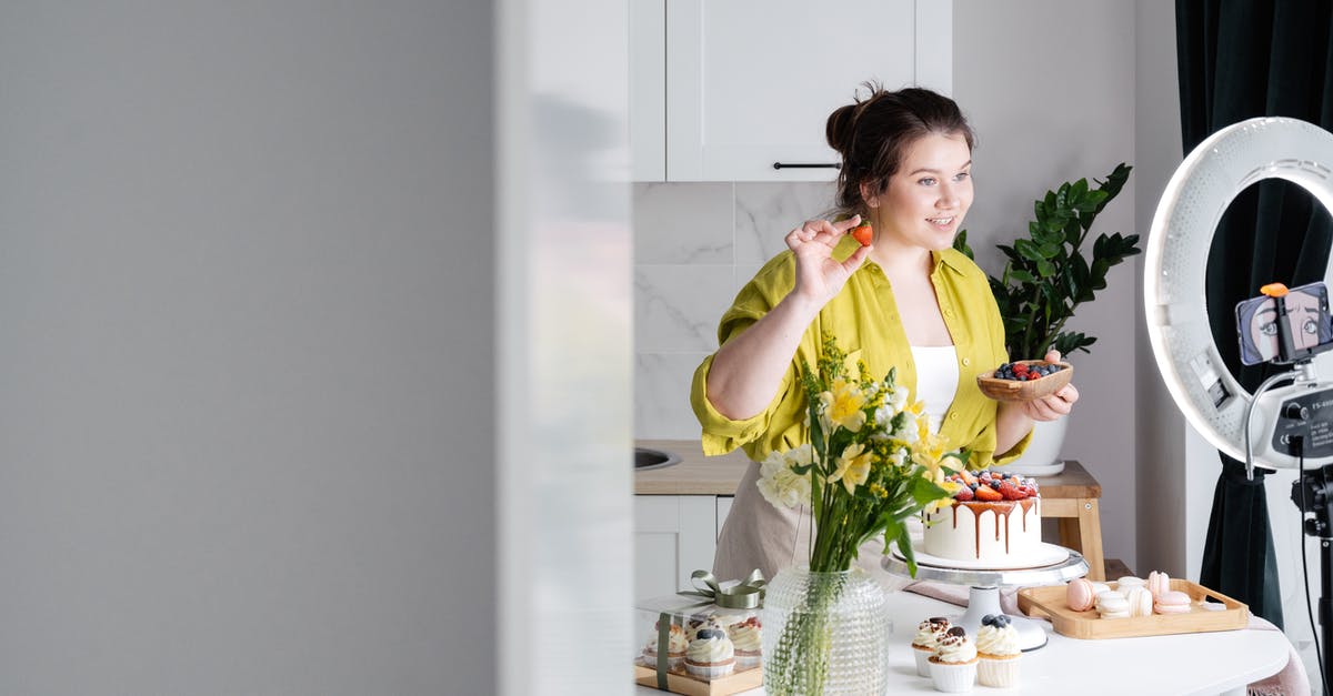 Valorant shows no internet connection - Delighted young female influencer in casual clothes smiling and demonstrating fresh berries while decorating appetizing cake during recording vlog on smartphone in kitchen