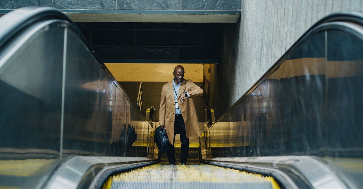 Vessels escaping host bodies over time - Contemplative black businessman riding escalator and looking at wristwatch