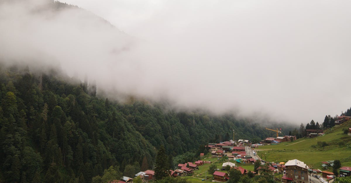 village overwritten - Houses on Green Grass Field Near Mountain Covered With Fog