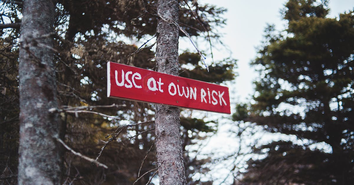 Warning sign while using scope as a tank destroyer - From below of red sign with use at own risk text on tree trunk in autumn forest