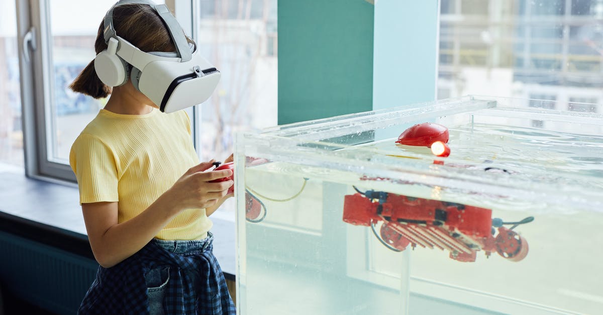 What's going on inside the game when a BUD switch activates? - Side view of little girl wearing VR goggles and exploring new robot with controllers in light room