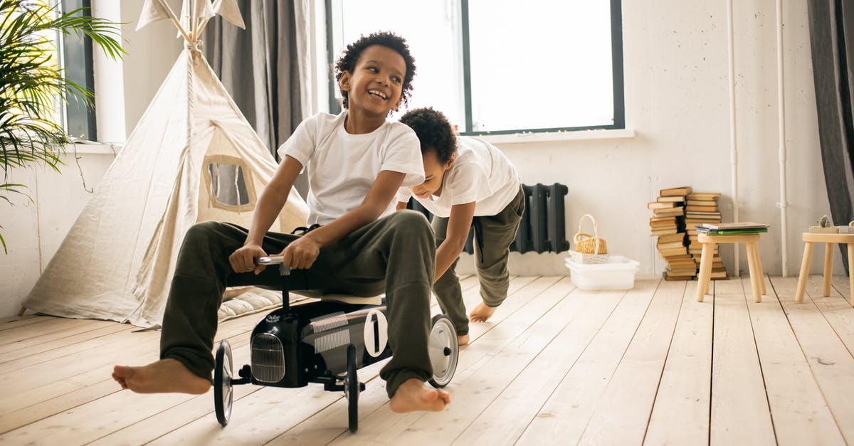 What's going on inside the game when a BUD switch activates? - Happy barefoot African American brothers in casual wear riding toy car while playing together in light room with blanket fort