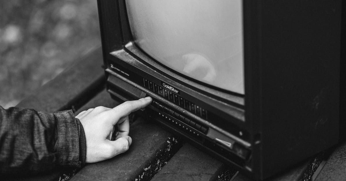 What are body parts used for? - Black and white of unrecognizable male pressing buttons on old fashioned television placed on wooden table in nature on blurred background