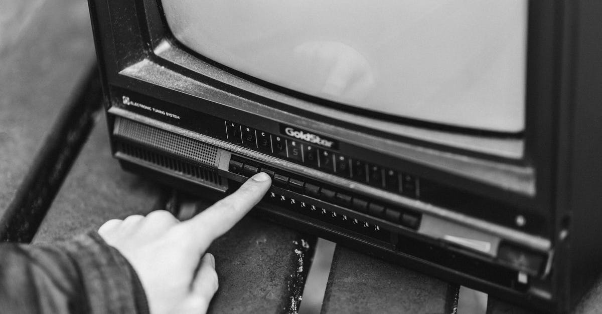 What are body parts used for? - Black and white from above of anonymous male switching channels on retro black television placed in wooden table on street