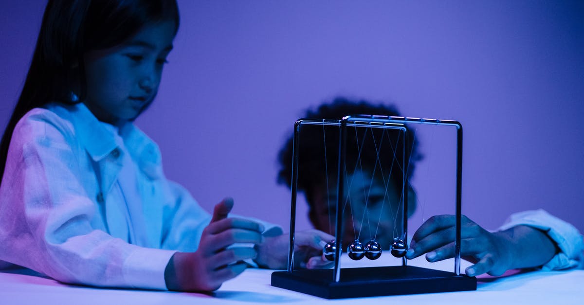 What are the moving glowing balls in slither.io? - Boy and girl playing with newton s cradle in a blue light