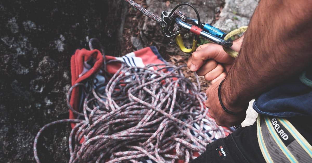 What are the special douchebag gear stats? - Unrecognizable climber with belay harness with carabines on rope standing near rocky cliff while preparing for mountaineering training in nature