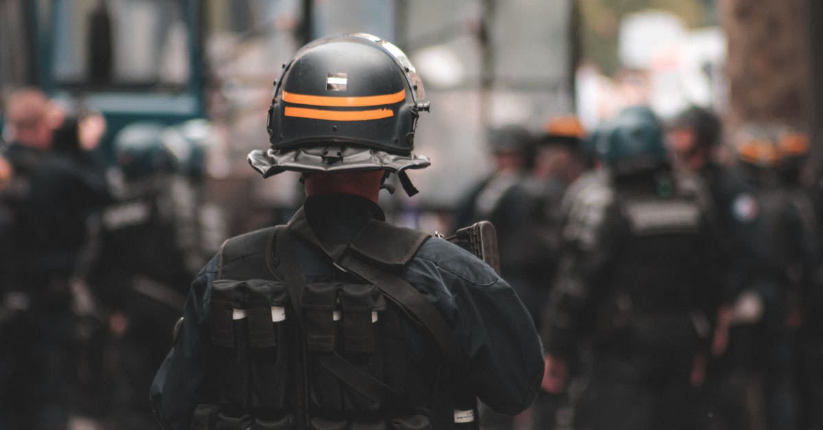 What are the special douchebag gear stats? - Back view of anonymous policeman in helmet and bulletproof vest maintaining law and order while standing on city street