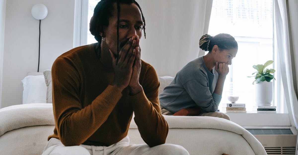 What are these Negative Lumps for? - Wistful concerned African American couple in casual clothing sitting on bed at home after having quarrel