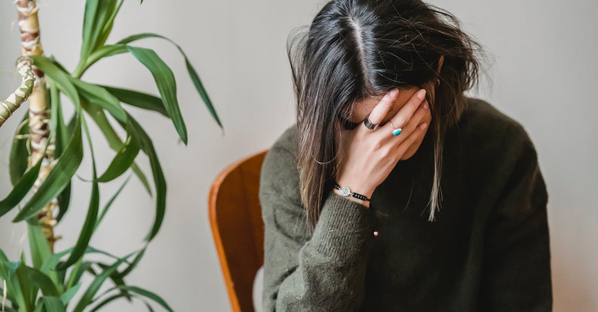 What are these Negative Lumps for? - Unrecognizable young upset female millennial with dark hair in stylish sweater covering face with hand while siting on chair at home