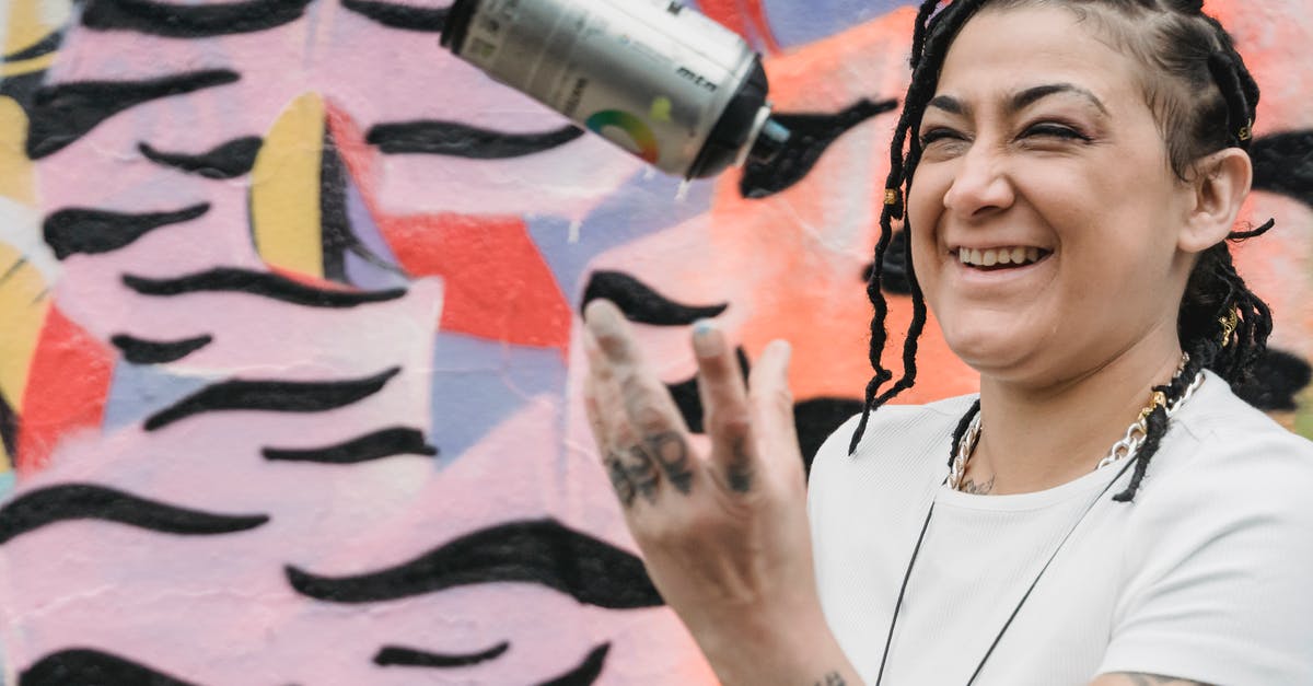 What can I expect to get in the Supply Chest? - Happy ethnic female artist with braided hair tossing up spray paint can while standing near wall with creative graffiti on street