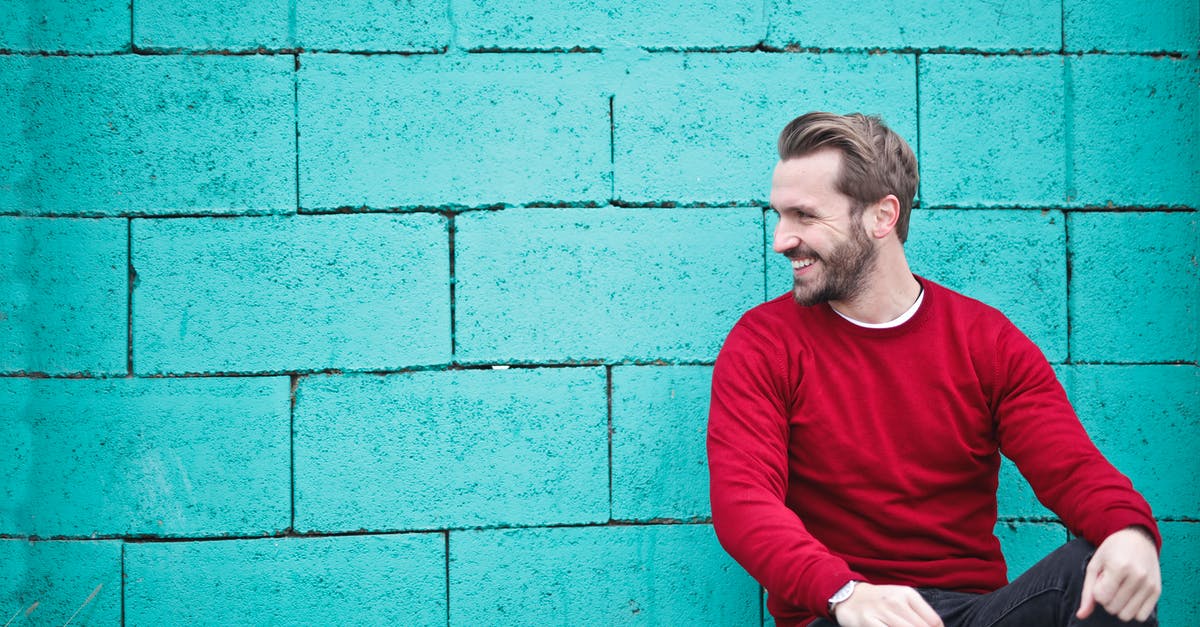 What colour is Pac-Man? - Man Wearing Red Sweatshirt and Black Pants Leaning on the Wall