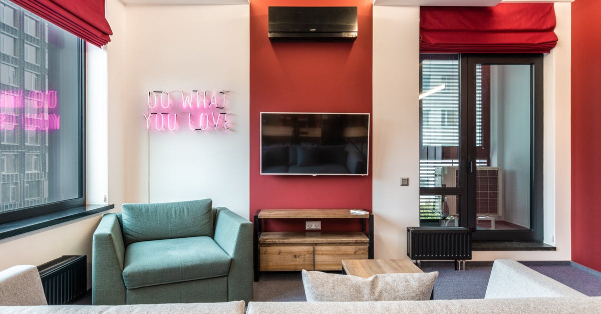 What do I put under the door in the hotel? - Interior of modern office lounge zone with sofa and armchair with table near window next to TV on wall and neon signboard with text do what you love near door