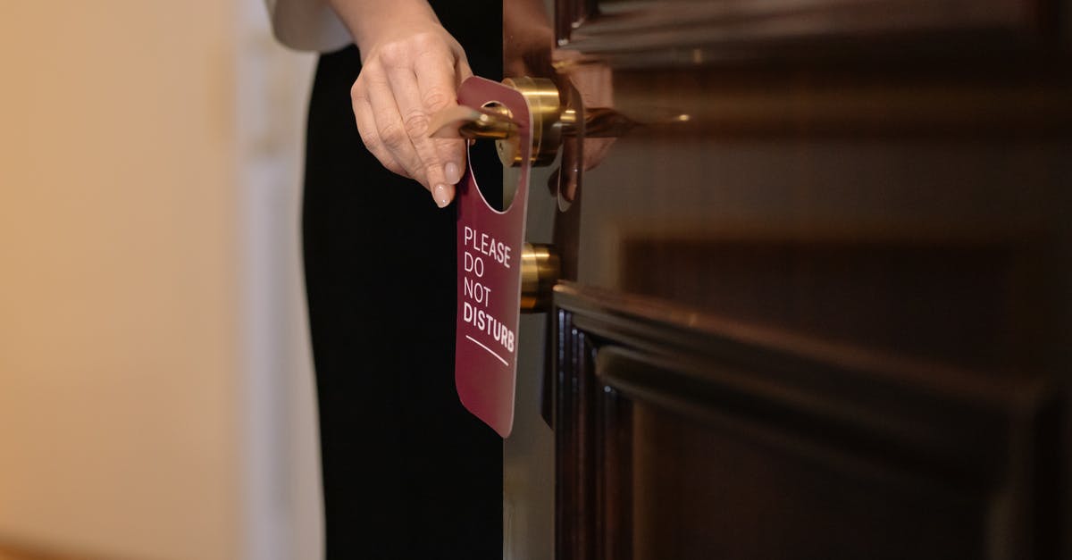 What do I put under the door in the hotel? - Woman Putting a Sign on the Door of a Hotel Room