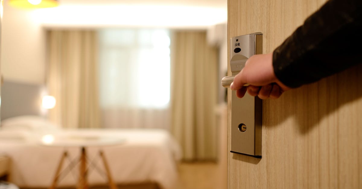 What do I put under the door in the hotel? - Person Holding on Door Lever Inside Room