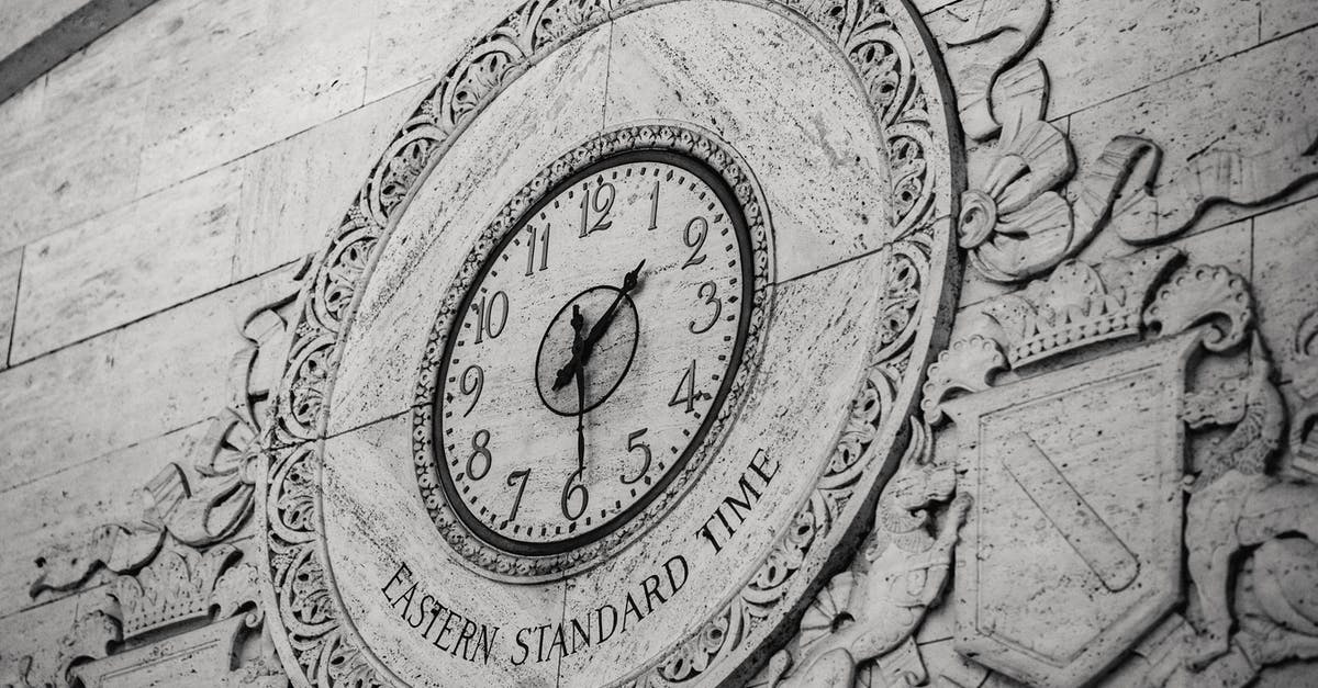 What do the circle of stones represent? - From below black and white of stone wall with ornamental details around clock showing Eastern Standard Time