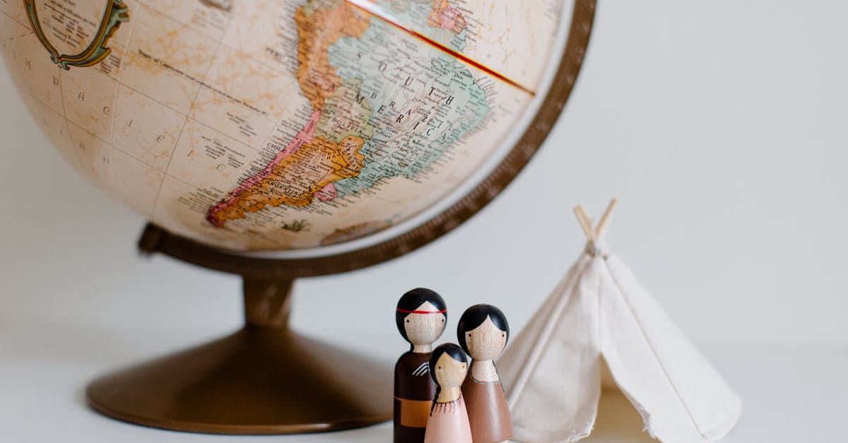 What do the gray exclamation points on the map mean? - From above of miniature toys tipi house and American Indian family placed near vintage globe against gray background at daytime