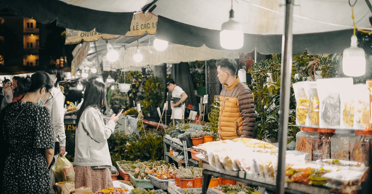 What does buying a wish in Sega's Aladdin do? - A Woman Holding a Cellphone Standing in Front of Food Stall