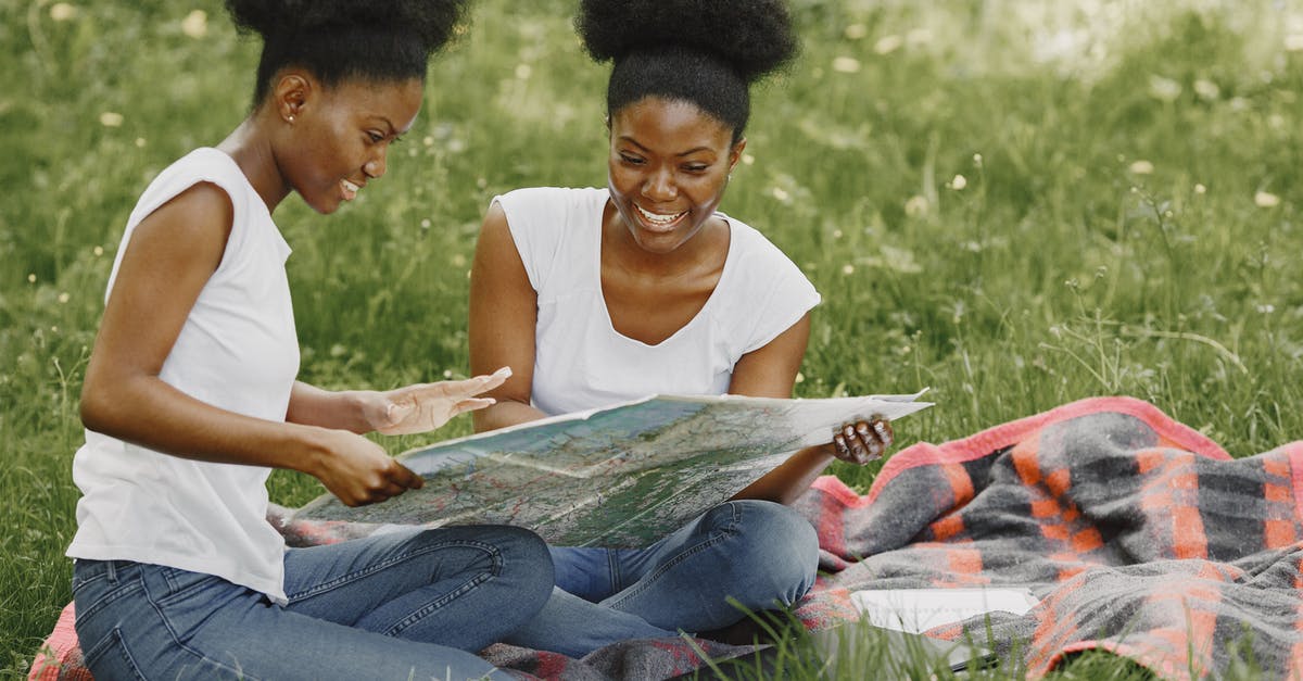 What does map ban mean? - Women Sitting on Picnic Blanket and Looking at a Map