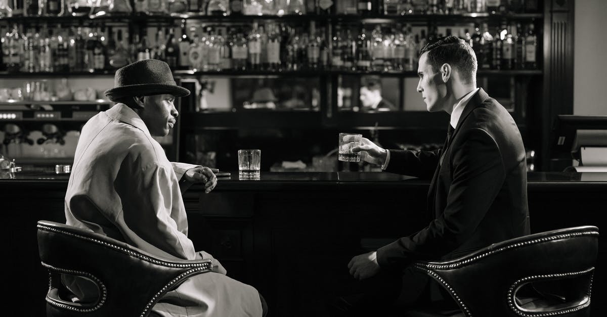 What does suspicious behaviour mean? - Monochrome Photo of Men Sitting in Front of Bar Counter