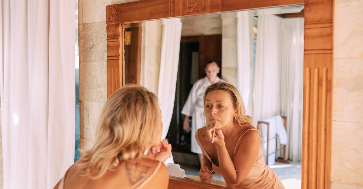 What does the mirror do? - Woman Looking in Mirror in Bathroom Doing Makeup