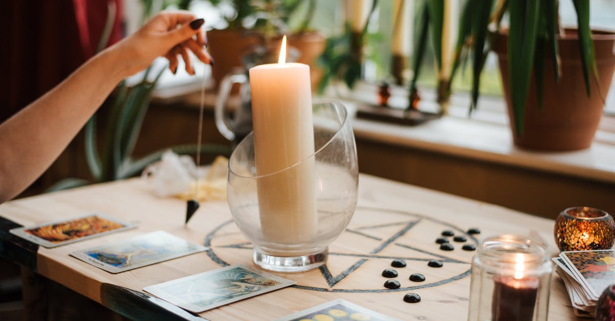 What is the highest effective enchantment level? - Crop unrecognizable female fortune teller with amulet near tarot cards and shiny candles during prediction process at home