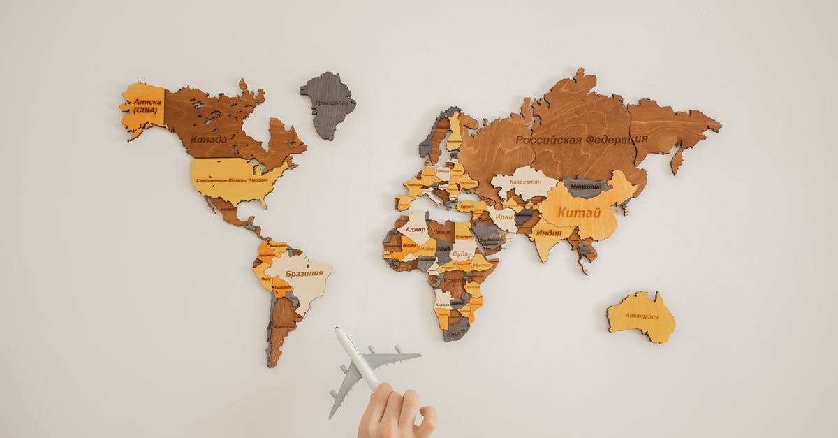 What is the name of the knife? - Crop unrecognizable person with toy aircraft near multicolored decorative world map with continents attached on white background in light studio