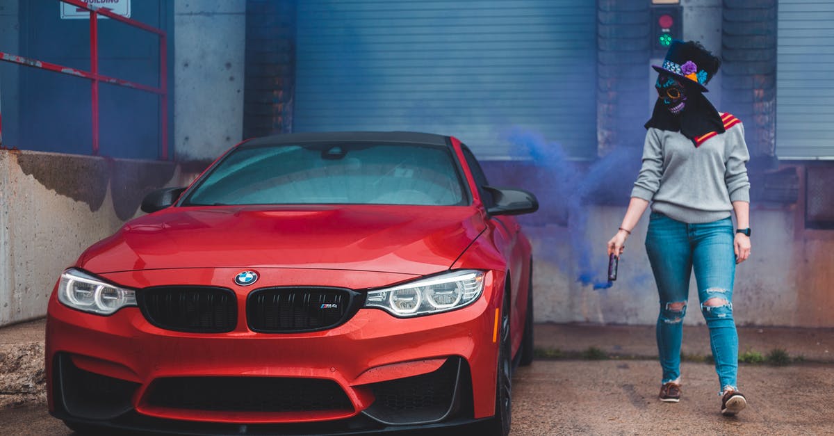 What is this blue smoke behind a wall? - Anonymous woman with smoke bomb near car