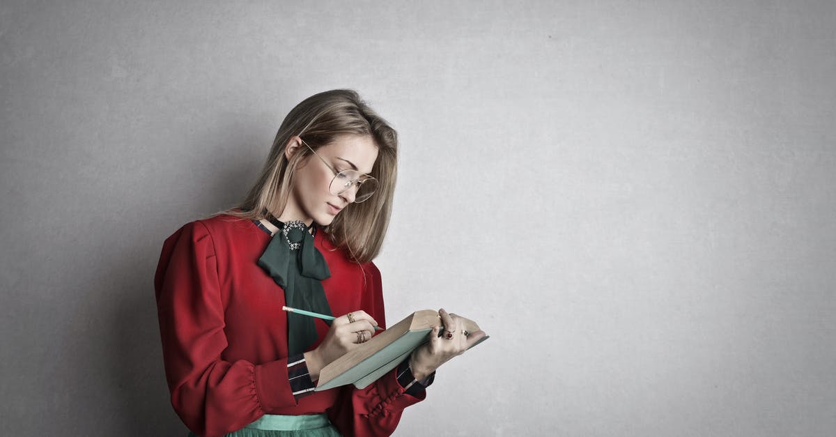 What memory size can a R4i work with? - Pensive attentive woman in glasses and elegant vintage outfit focusing and taking notes with pencil in book while standing against gray wall