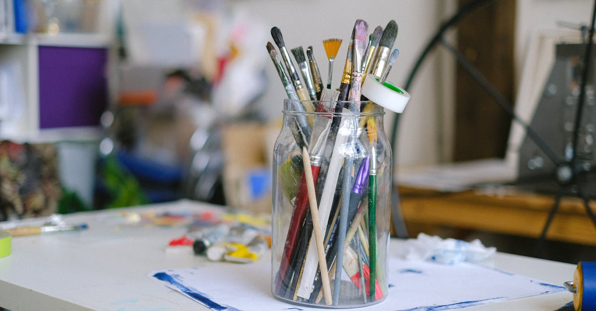 What Minerals are used in crafting? - Glass jar with paintbrushes on desk with paint tubes in professional art workshop