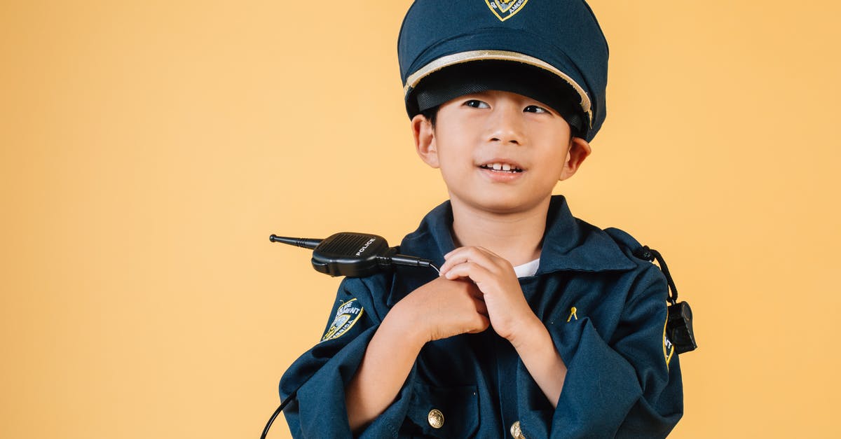 What order should I play the Half-life series in? - Pleasant Asian boy in police uniform and cap looking away while standing with hands near chest in studio on yellow background