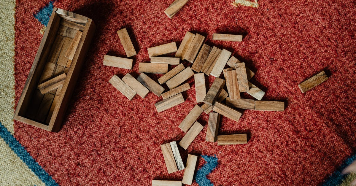 What this secret floor puzzle at the entrance activates? - Top view of wooden box and pile of blocks for playing in jenga tower game arranged on floor carpet