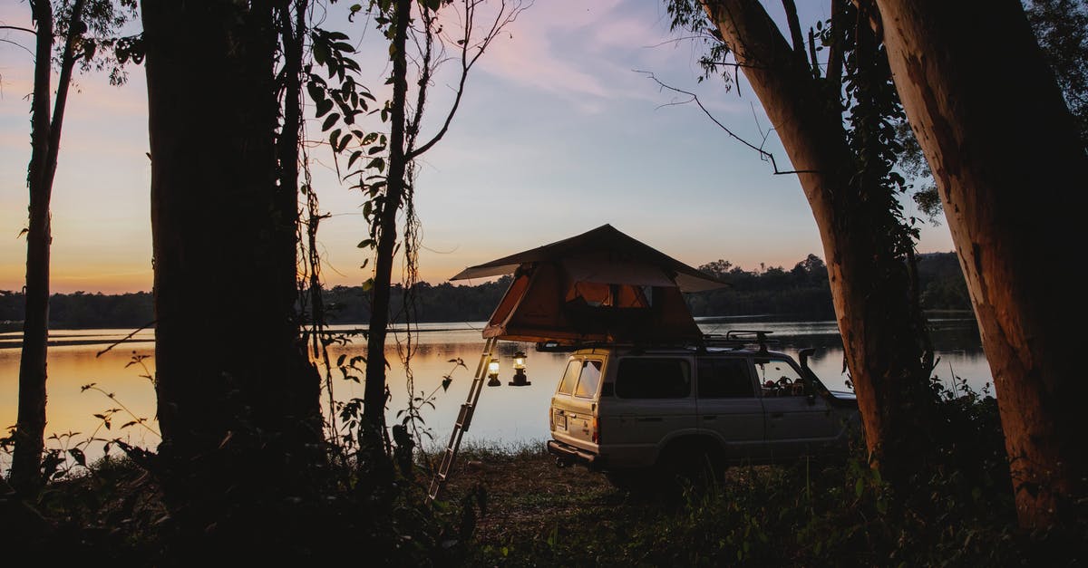 Whats happening to my off shore money? - Picturesque scenery of camping tent placed on SUV car parked on coast of peaceful lake located in woods against amazing sunset sky