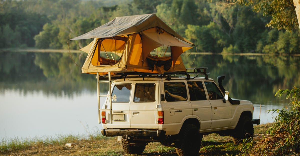 Whats happening to my off shore money? - Off road car with tent on roof parked on lake shore in forest