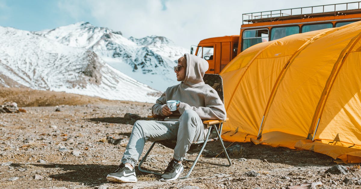 When is the "Exploration Bonus" awarded in Escape from Tarkov? - Full length of male camper sitting on folding chair next to tent in middle of mountain valley and enjoying views