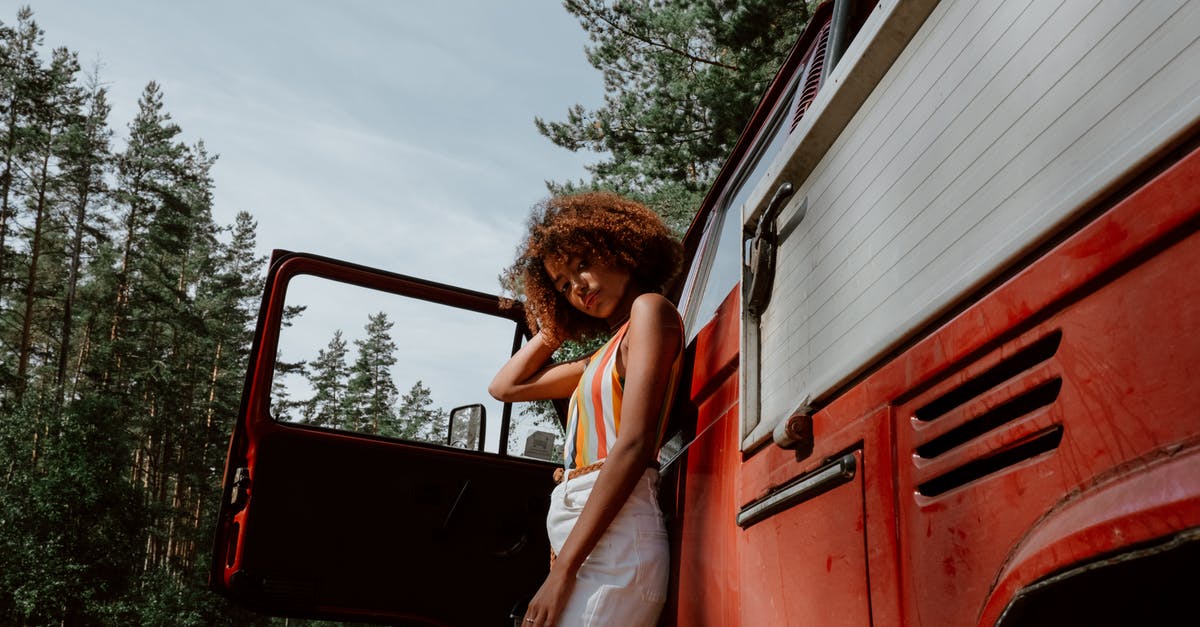 Where has my car gone? - Woman in Blue Tank Top Sitting on Red Car