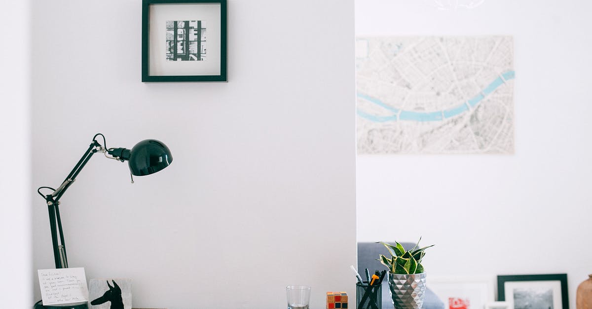 Where is this room located on the map? - Lamp with cup of stationery placed on wooden desk with potted plant in light cozy apartment