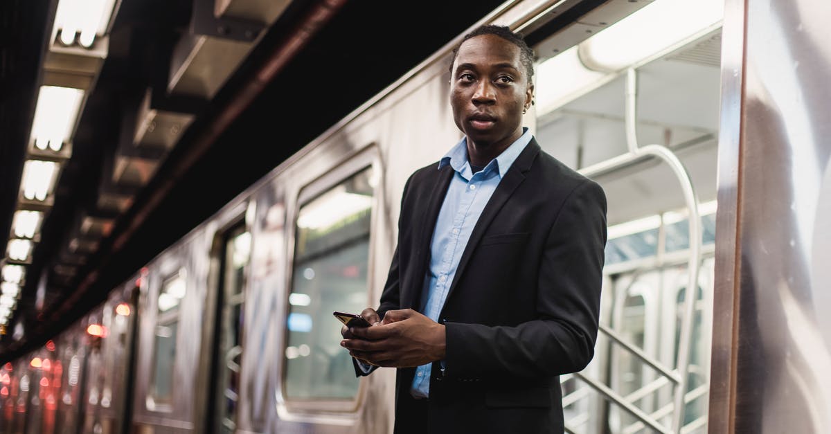 Where to get the hammer suit - Serious African American man in office wear with mobile phone in hands getting off underground train