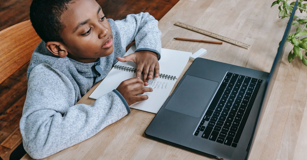 Which DLC I need to concentrate development in EU4? - From above of smart cute African American boy studying online with netbook while sitting at table with notebook and pencil