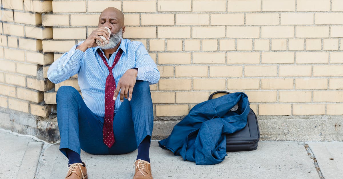 Which guns can break the windows on presidential plane? - Full body of mature African American bearded businessman in blue trousers and light shirt with maroon tie sitting on ground at brick wall and drinking beverage from tin can