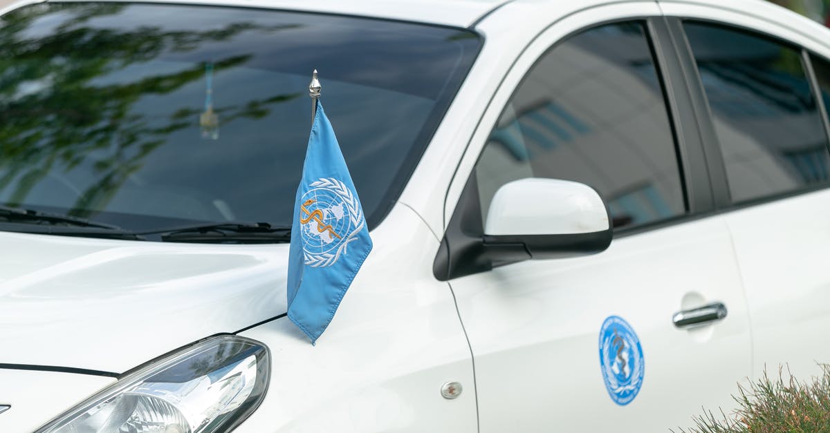 Who invented directional damage indicator [closed] - Contemporary white car decorated with blue World Health Organization flag and sticker parked on street