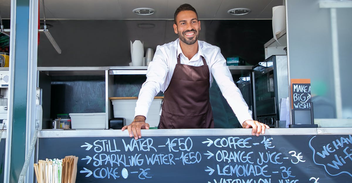 Who is the elf from ESO trailers - Low angle of ethnic seller wearing uniform standing at counter in food trailer and smiling happily