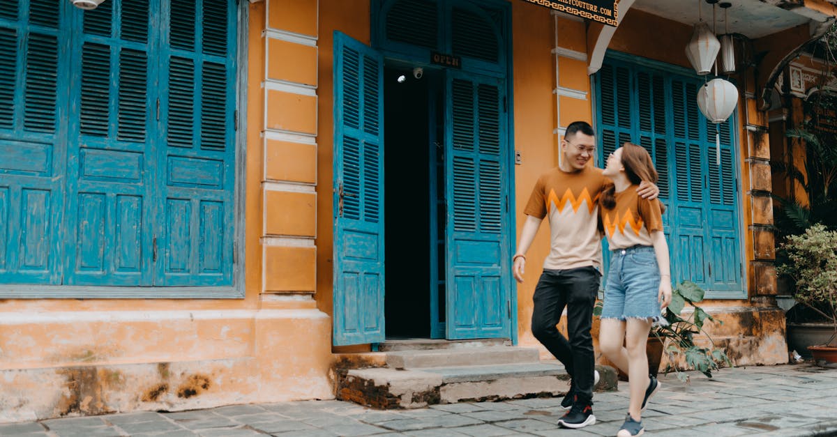 Why batches of same items are not next to each other? - Full length of happy Asian couple in same t shirts hugging and looking at each other while walking on street near entrance of colorful building